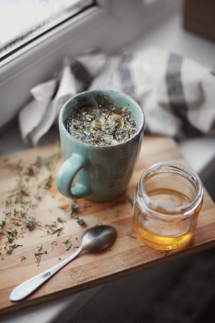 Warm herbal tea and honey on a wooden board by the window, perfect for a cozy day.
