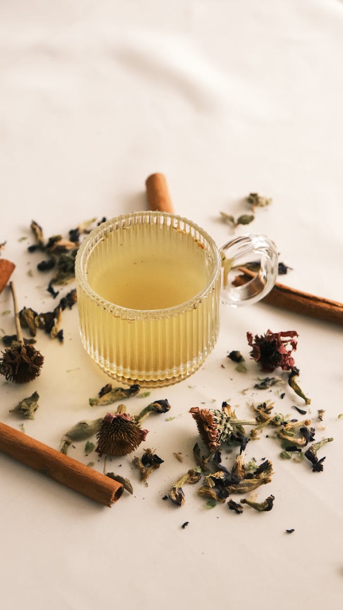 services-01 Warm herbal tea in a glass cup with dried flowers and cinnamon sticks on a light background.