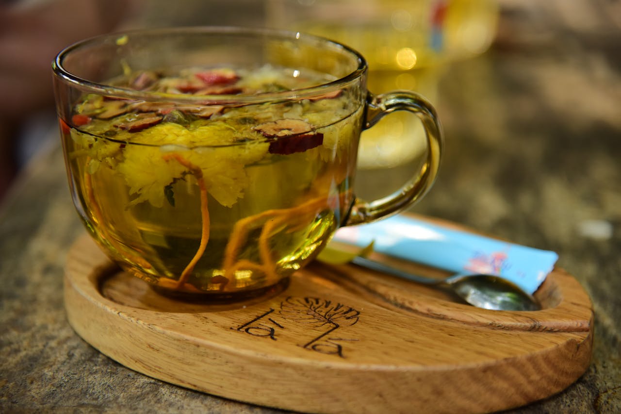 Close up of herbal tea with flowers in a glass cup on a wooden tray. Perfect for relaxing.
