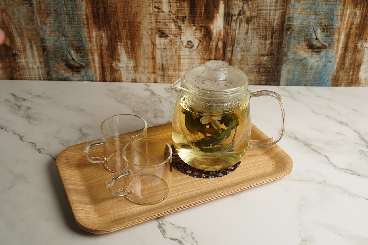 services-02 Stylish glass teapot with herbal infusion on a wooden tray, perfect for a cozy tea time.