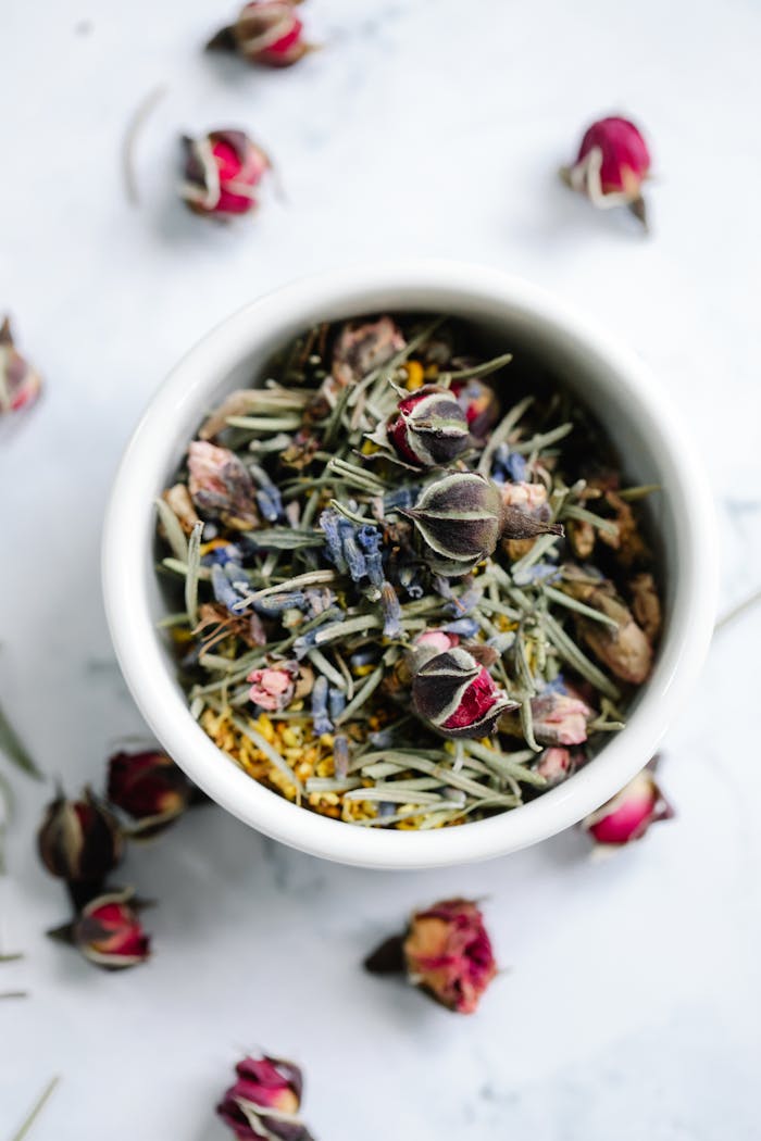 services-03 A close-up top view of a bowl filled with a herbal tea blend of dried roses and lavender.